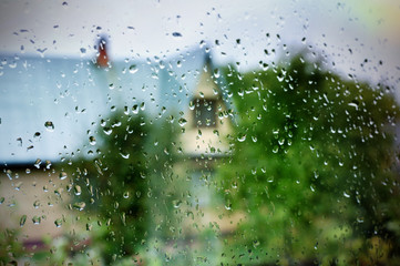 wet glass window of a country house, blurred view of the countryside from the room
