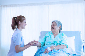 Nurse reassuring her patient on bed in hospital / healthcare medical concept. copy space