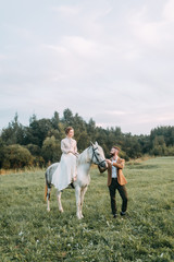 Wedding in American style, on a ranch with a horse. Walk couples in the fields at sunset, with friends and on horseback. Modern couple and ideas for the ceremony.
