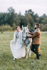 Naklejka na ściany i meble Wedding in American style, on a ranch with a horse. Walk couples in the fields at sunset, with friends and on horseback. Modern couple and ideas for the ceremony.