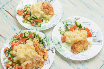 Mashed potatoes with chop and fresh vegetable salad in a plate on wooden background.