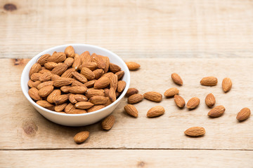 Almonds in a white cup rests on a wooden table