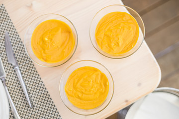 Three mango mousses in glass bowls
