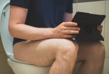 Man using tablet pc in the toilet.