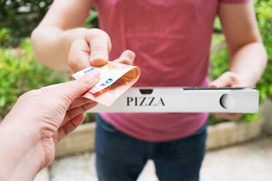 Man delivering pizza in box and taking payment.