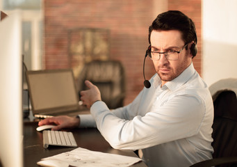 close up.businessman with a headset sitting at his Desk