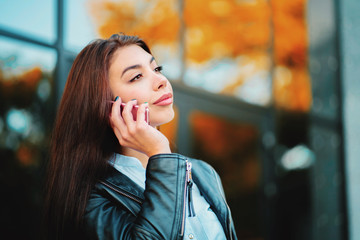 Business woman with smartphone close up near office building. Girl have conversation with cell phone. Beautiful caucasian young woman talking with mobile device.