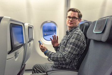 Mann zeigt der Stewardess im Flugzeug, dass er in 5 Sekunden sein Mobile Device abschaltet