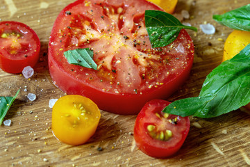 Sliced tomatoes and basil on a wooden board