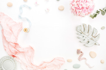Round frame of hydrangea flower bouquet, eucalyptus branch, pastel pink blanket, monstera leaf plate on white background. Flat lay, top view mockup with space for text.