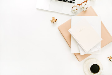 Modern home office desk with laptop, notebook, coffee cup, cotton branch on white background. Flat lay, top view minimal workspace.