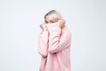 Portrait of girl pulling her pink sweater over head. Woman with scared look disappearing in her...