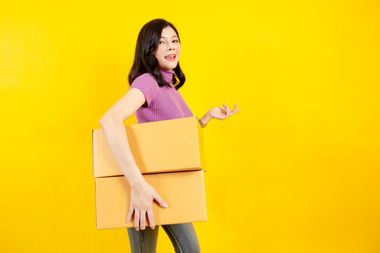 Portrait Of The Beautiful Asian Girl Carrying A Parcel Boxes Close Up On Yellow Background.  Conceptual Of Online Shopping In Present.