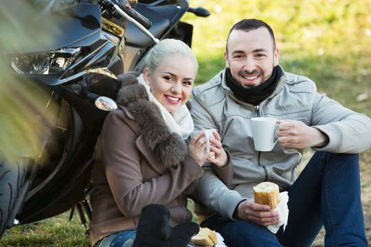 Positive young smiling couple having picnic with coffee