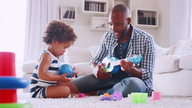 Young black dad playing with young daughter in sitting room