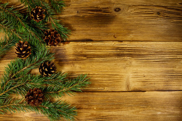 Christmas composition with fir tree branches and cones on wooden background. Top view, copy space