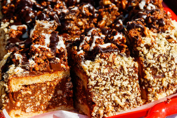 Sliced snickers cake close-up. Chocolate cake with peanuts on a tray