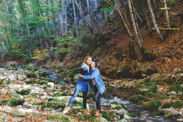 Naklejka na ściany i meble Two young girls friends walking and having fun in the autumn forest. Walk in the woods. Girlfriends hiking in the fall, laugh and hug. 