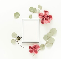 Flowers background composition. Photo frame mock up, dried flowers and eucalyptus branches on white background.Holiday concept. Flat lay, top view, copy space