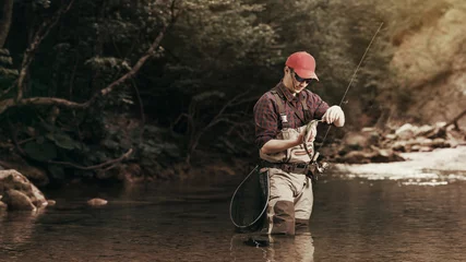 Poster Visser gevangen een vis neemt de haak. Forel vissen op de rivier. © kuznetsov_konsta