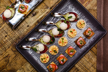 Fresh tasty canapes on a tray - ice-cream, fruit dishes, salad dishes
