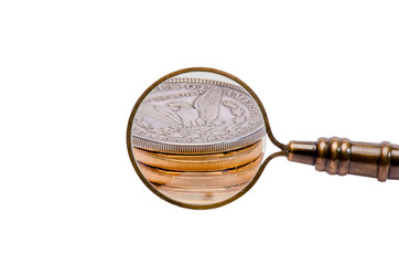 Gold and silver coins viewed through antique magnifying glass with handle.