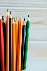 Multicolored pencils on wooden background. Many beautiful multicolored pencils on the table....