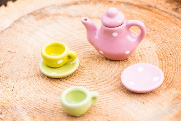 A small teapot and two porcelain cups stand on a wooden background. On a small plate lies a piece of delicious cake. Everything is ready for tea.