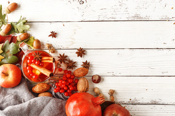 Autumn composition of a cup of warming tea, autumn leaves, fruits and spices on a white wooden table. Top view. Copy space