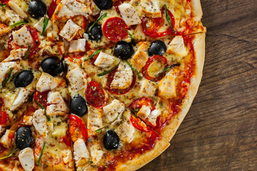 sliced Pizza with Chicken meat, Mozzarella cheese, tomato, olive. Italian pizza on wooden background