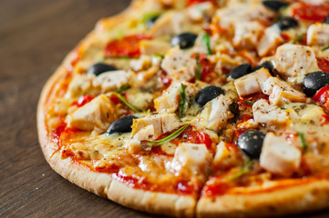 sliced Pizza with Chicken meat, Mozzarella cheese, tomato, olive. Italian pizza on wooden background