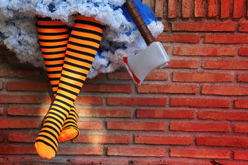 Halloween! Witch waiting candy with a bloodied axe. Girl's legs in the striped orange and black...