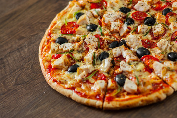 sliced Pizza with Chicken meat, Mozzarella cheese, tomato, olive. Italian pizza on wooden background