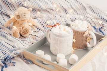 Obraz na płótnie Canvas Hot chocolate with marshmallows on soft plaid background with Christmas lights. Perfect winter time treat.