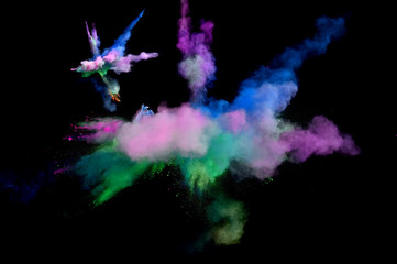 Abstract forms of powder paint and flour combined  together explode in front of a black background to give off abstract  multi colored cloud forms.