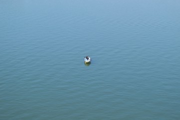 Fisherman in boat, alone on quiet, blue water