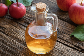 A bottle of apple cider vinegar with fresh apples