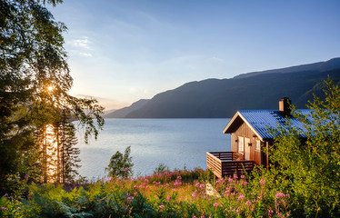 Wooden summerhouse with terrace overlooking scenic lake at sunset in Norway Scandinavia - obrazy, fototapety, plakaty