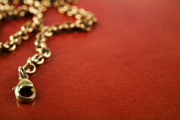 Fototapeta na wymiar Gold chain on reddish brown leather background.