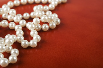 White pearl necklace on red leather background.