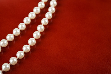 White pearl necklace on red leather background.