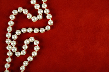 White pearl necklace on red leather background.