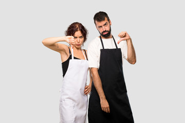 Couple of cooks showing thumb down sign with negative expression on grey background