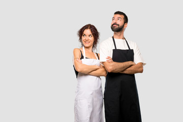 Couple of cooks looking up while smiling on grey background