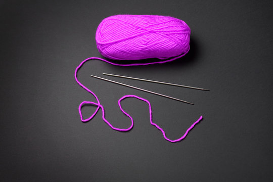 pink ball of woolen yarn for knitting on black background