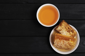 Honeycombs and honey on a black wooden background. copy space. Flat lay. 