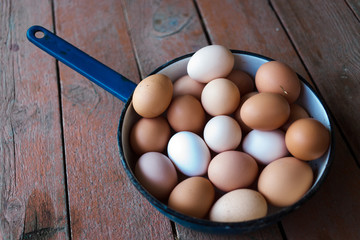  Chicken eggs from the farm. Eggs lie in a metal blue bowl on a wooden background