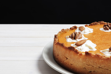 Closeup of pumpkin pie with whipped cream. Nuts and pumpkin. Pumpkin pie on a white wooden table.