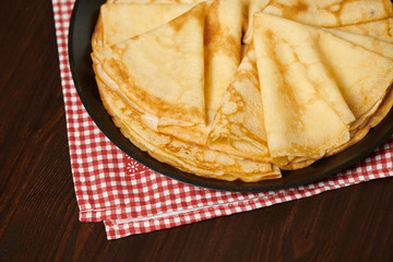 Crepe closeup, thin pancake on a frying pan, wood background