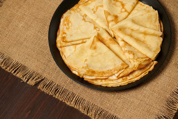 Crepe closeup, thin pancake on a frying pan, wood background